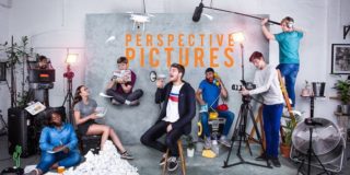 A group of young people striking poses in a studio with the words 'Perspective Pictures' overlaid on the backdrop. Rupert Rixon sits in the middle holding a megaphone.