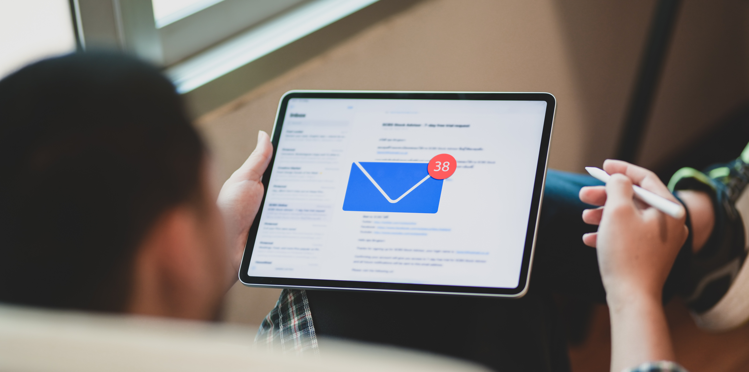 A man checks email on a tablet. An envelope icon shows 38 new messages.