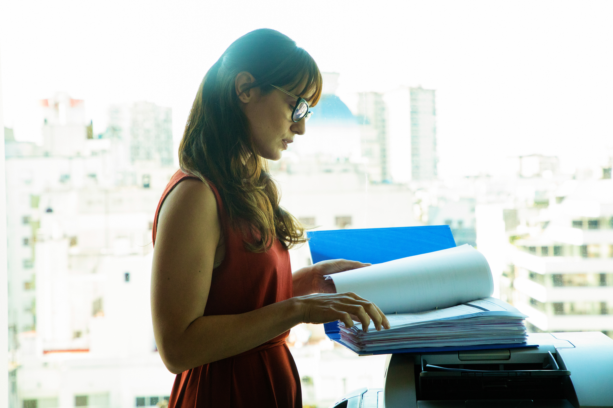A woman at a copier with a large file