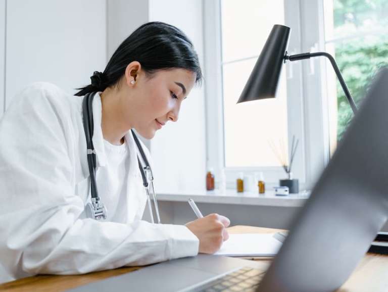 Healthcare provider uses her laptop to conduct telehealth while sitting at her desk.