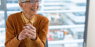 A smiling woman sits in front of her computer