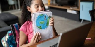 Dedicated student showing her planet earth drawing during video class at home to demonstrate the benefits of video conferencing in education