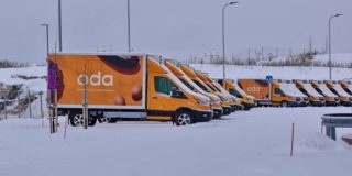 Photograph of orange Oda delivery fans lined up in the snow.