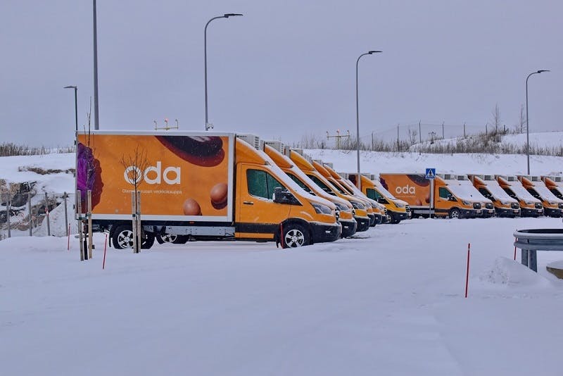 Photograph of orange Oda delivery fans lined up in the snow