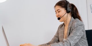 A smiling government contact center agent with headset delivers excellent citizen experience as she sits in front of her laptop