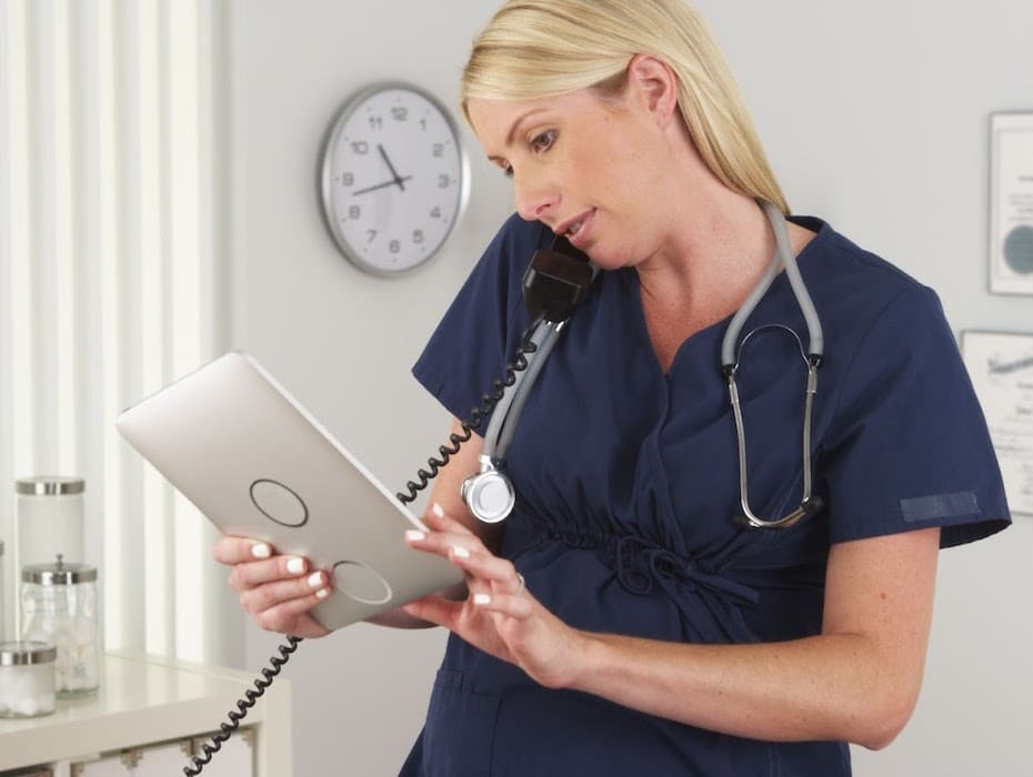 A healthcare provider juggles a phone and tablet to work on a prior authorization request