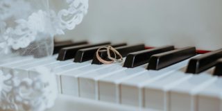 Golden rings on piano keyboard under veil with ornament during festive event in daytime