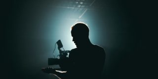 Silhouette of Man Standing in Front of Microphone