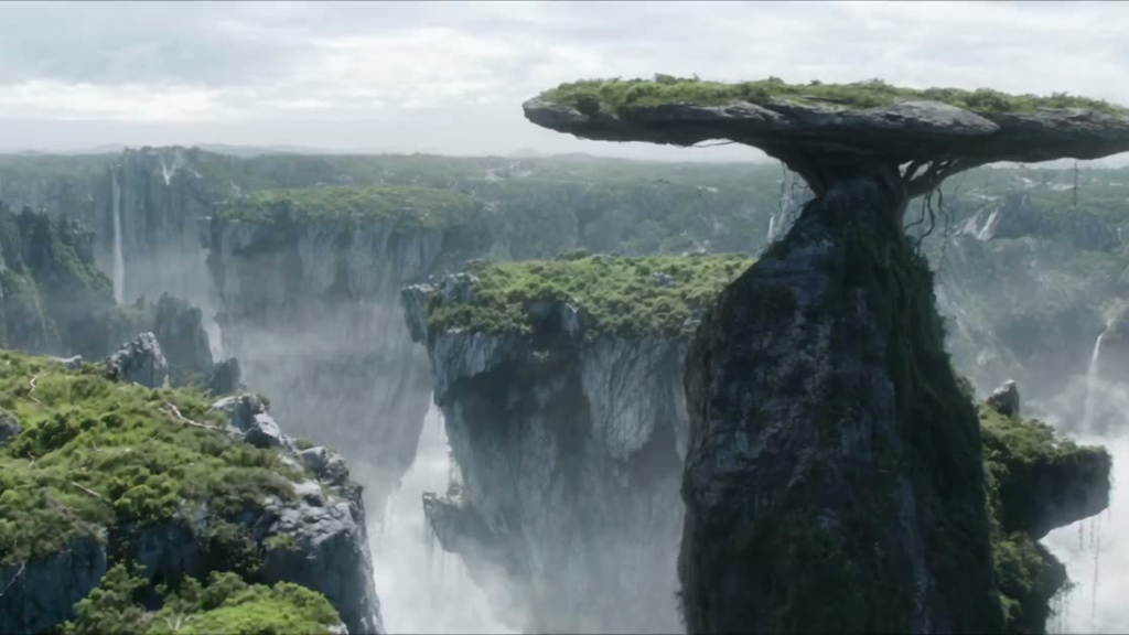 A dramatic landscape showing a tall rock pillar with a flat, grassy top, forming a mushroom-like formation over a misty canyon.